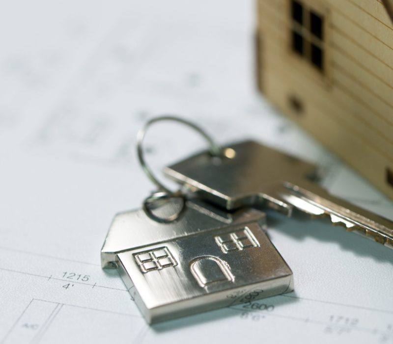 House key with house model keychain on house layout plan